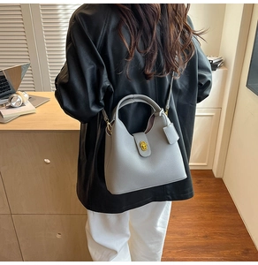 Grey pebbled leather bucket bag featuring a gold-tone twist lock for professional style