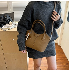 Sac seau marron avec texture à rayures verticales et breloque en perles colorées au bureau