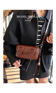Detail of vintage brown glossy leather crossbody bag with double buckle flap design
