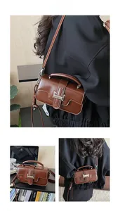 Detail of vintage brown leather crossbody bag with metal buckle and glossy texture