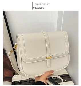 Détail d'un sac carré en cuir litchi blanc crème avec une boucle en métal doré chic