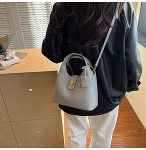 Detail view of grey litchi grain leather bucket bag with gold lock and shoulder strap