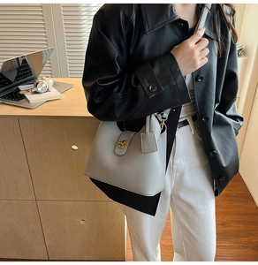 Grey pebbled leather bucket bag with gold twist-lock shown in a professional office setting