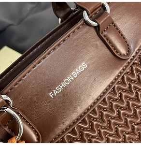 Macro detail of brown leather bag showing wavy quilted stitching and silver metal hardware