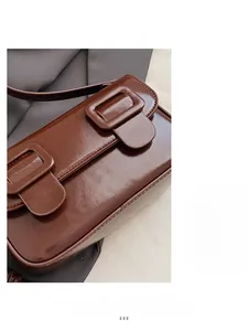 Detail of dark brown leather handbag with glossy finish and dual buckle flap closure