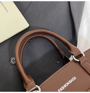 Detailed macro view of dark brown leather handbag handle and silver metal hardware