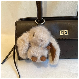 Detailed view of a soft plush rabbit charm accessory with leather accents on a handbag