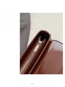 Close-up of smooth silver metal zipper on dark brown glossy leather baguette bag