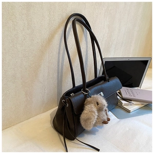 Detail of dark brown leather shoulder bag with buckle and plush rabbit charm