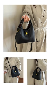 Close-up of black lychee grain leather bucket bag with elegant golden twist lock hardware