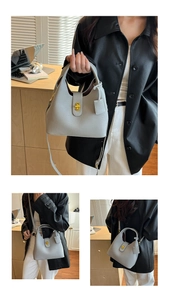 Detail of light gray leather bucket bag with gold swivel lock and versatile straps