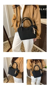 Details einer schwarzen Plissee-Tasche mit Ethno-Perlenanhänger und Schultergurt