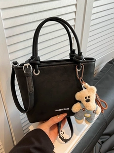 Minimalist black matte leather bucket bag with top handle and plush bear charm