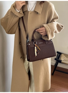 Close-up of brown textured bag with V-shaped weave, beaded charm and leather handle