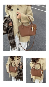 Détail d'un sac seau vintage en cuir marron avec texture verticale et pompon décoratif