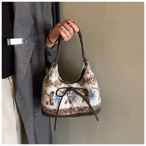 Chic plush tote bag with vintage print, brown bow detail and leather straps on model