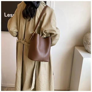 Detail of brown litchi pattern leather bucket bag with metal buckle on shoulder strap