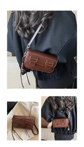 Detail view of the brown vintage crossbody bag with a glossy finish and double buckles