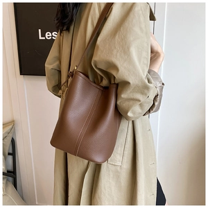 Detail of brown litchi pattern bucket bag with adjustable gold buckle and leather strap
