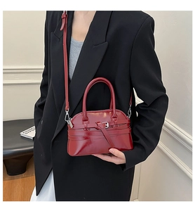 Close-up of a burgundy patent leather square bag with metallic buckle and glossy finish