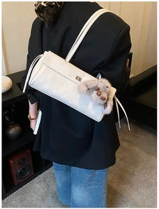 White quilted shoulder bag with plush bunny charm shown on a female model