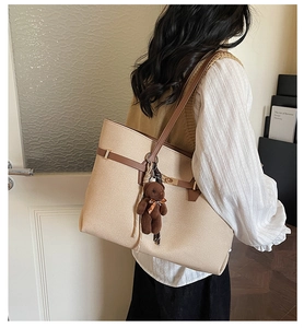 Detailed side view of beige large tote bag with brown straps and cute bear charm