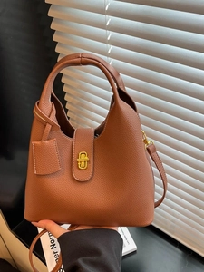 Brown lychee leather bucket bag with gold lock and adjustable strap for versatile styling