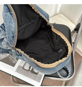 Vue détaillée du sac à dos en jean montrant l'intérieur spacieux et la poche zippée