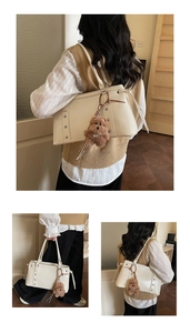 Detail view of cream patent leather underarm bag with metal studs and plush bear charm