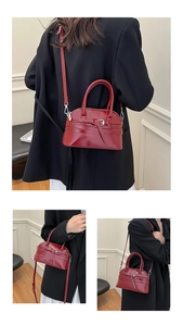 Detail of red vegan leather crossbody bag with decorative straps and metal buckles