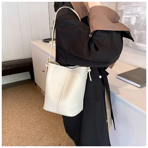 Chic cream bucket bag with litchi grain leather shown on model in a minimalist setting