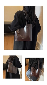 Detail of wax oil leather tote bag featuring wooden pendant and embossed logo text