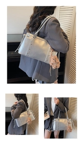 Detail view of silver metallic tote bag with studs and a brown plush bear charm