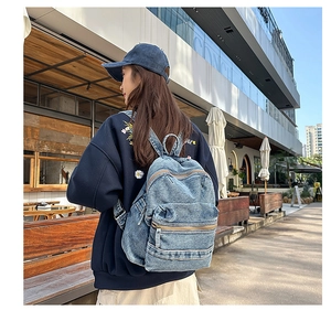 Gros plan du sac à dos en jean bleu vintage avec fermetures en métal et texture délavée