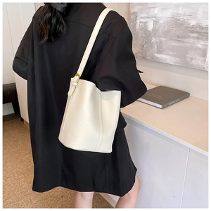 Vue détaillée d'un sac seau en cuir grainé blanc avec boucle dorée et bandoulière