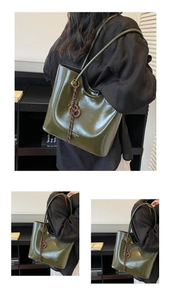 Detail of dark green glossy tote bag with shoulder strap and woven charm detail