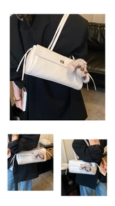 Detailed view of white quilted shoulder bag with silver twist lock and puppy pendant