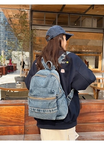 Détail du sac à dos en jean délavé avec doubles fermetures éclair et bretelles