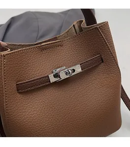 Detail of caramel lychee grain leather handbag featuring silver metal turn-lock closure