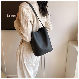 Détail d'un sac seau noir en cuir grainé avec une boucle en métal doré élégante