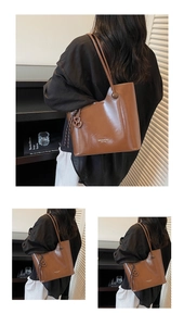 Close-up of brown leather bucket bag with brand logo and polished strap detailing