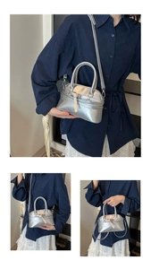 Detail of silver metallic handbag showing the buckle strap design and versatile carry modes