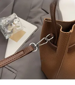 Detailed macro view of silver metallic buckle on brown pebble leather bucket handbag