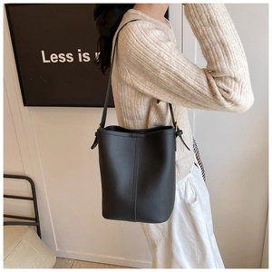 Side view of black bucket bag in lychee texture leather with gold metal hardware