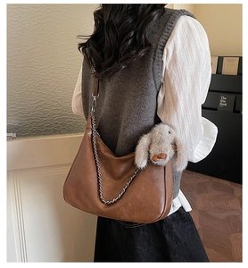 Side view of brown vintage hobo bag with silver chain and a plush rabbit pendant