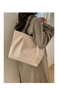 Close-up of the large canvas tote bag showing the dark brown leather straps and metal buckles