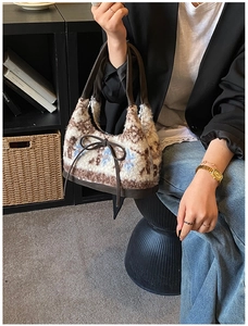 Detail of plush shearling tote bag featuring vintage floral patterns and a ribbon bow