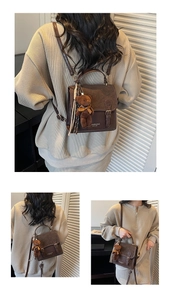 Detalle de bolso vintage marrón con colgante de osito de peluche y hebilla metálica