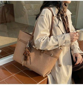Detail of vintage brown tote bag with metal twist lock and cute plush bear charm