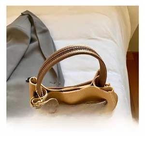 Détail du sac seau en cuir beige grainé avec fermoir rotatif en métal et breloque ours